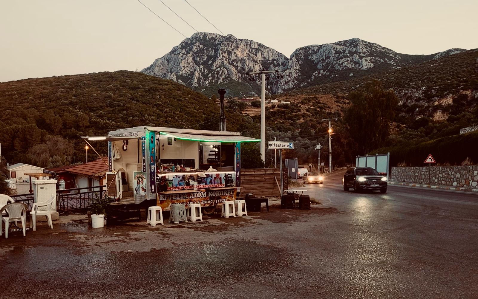 Eftelya Atom Kokoreç'in Karaburun yolu kenarındaki büfesi, arkasında Karaburun dağları, akşamüstü.